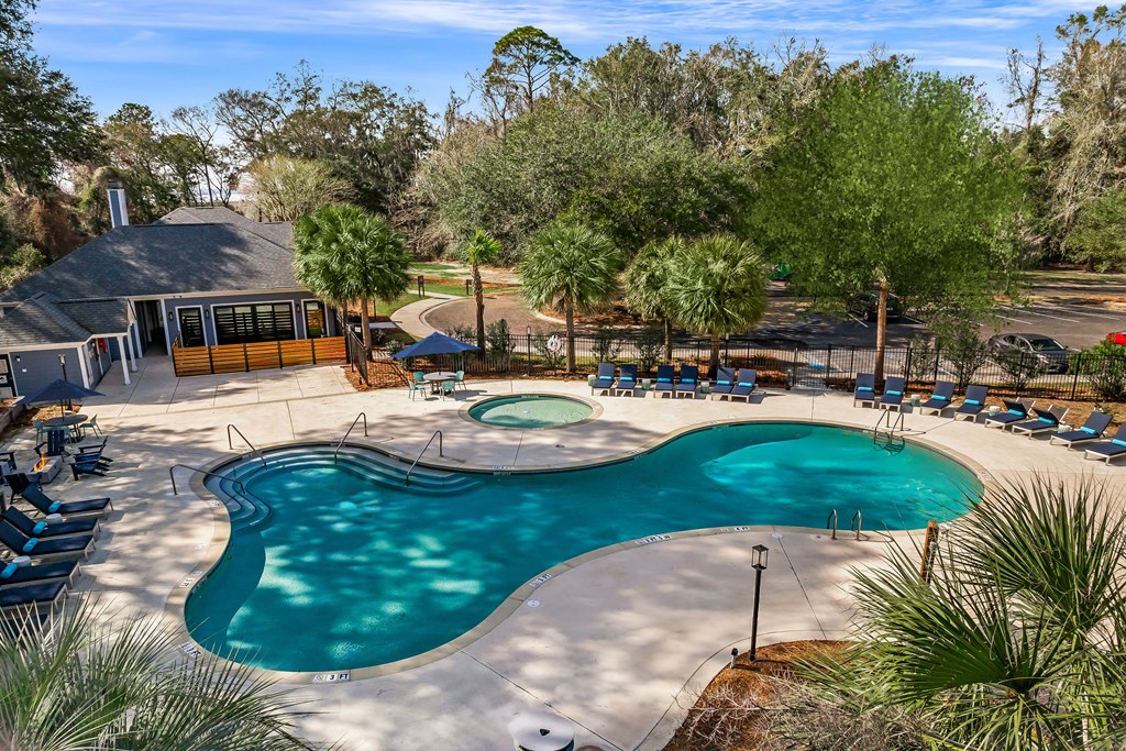 A large outdoor swimming pool surrounded by trees and a house.