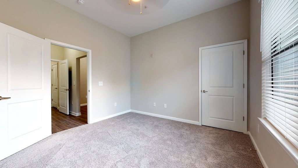 a bedroom with a carpeted floor and a door to a closet