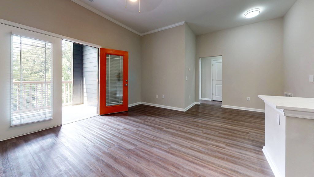 an empty living room with a red door and a window