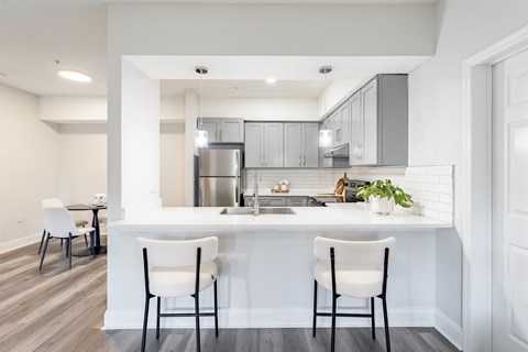 A kitchen with white chairs and a white counter.