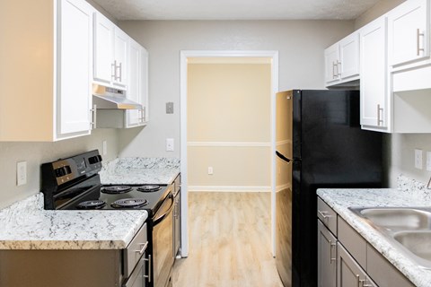 Kitchen with black appliances and wood like flooring at twin Springs, Norcross, GA