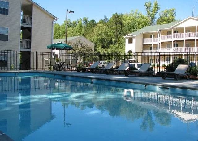 a large swimming pool with chairs and a umbrella