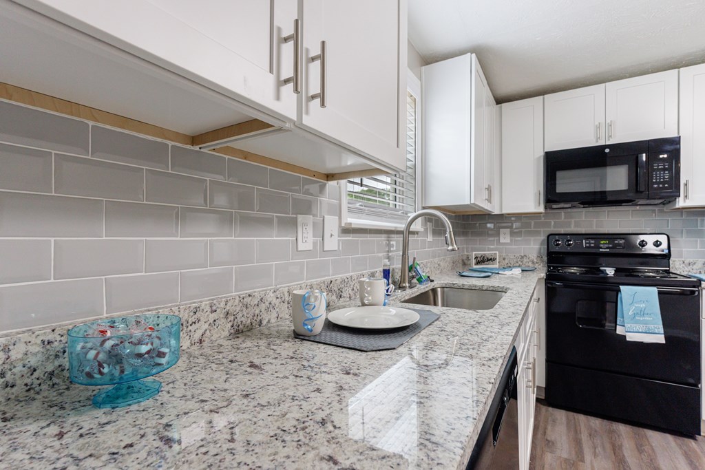 A kitchen with granite countertops and white cabinets.