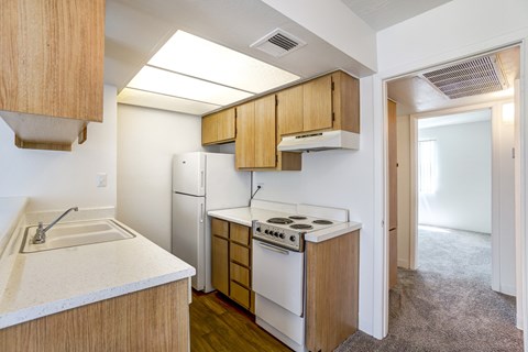 A kitchen with a white stove top oven and white refrigerator.