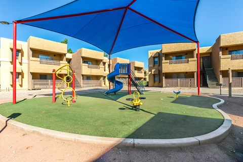 A playground with a blue canopy and a yellow swing set.