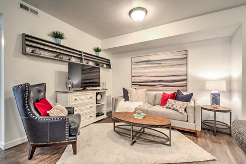 A living room with a black leather chair and a grey couch.