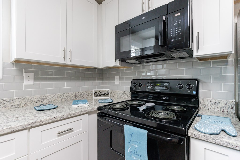 A kitchen with a black stove top oven and white cabinets.