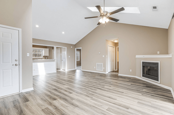 an empty living room with a fireplace and a ceiling fan