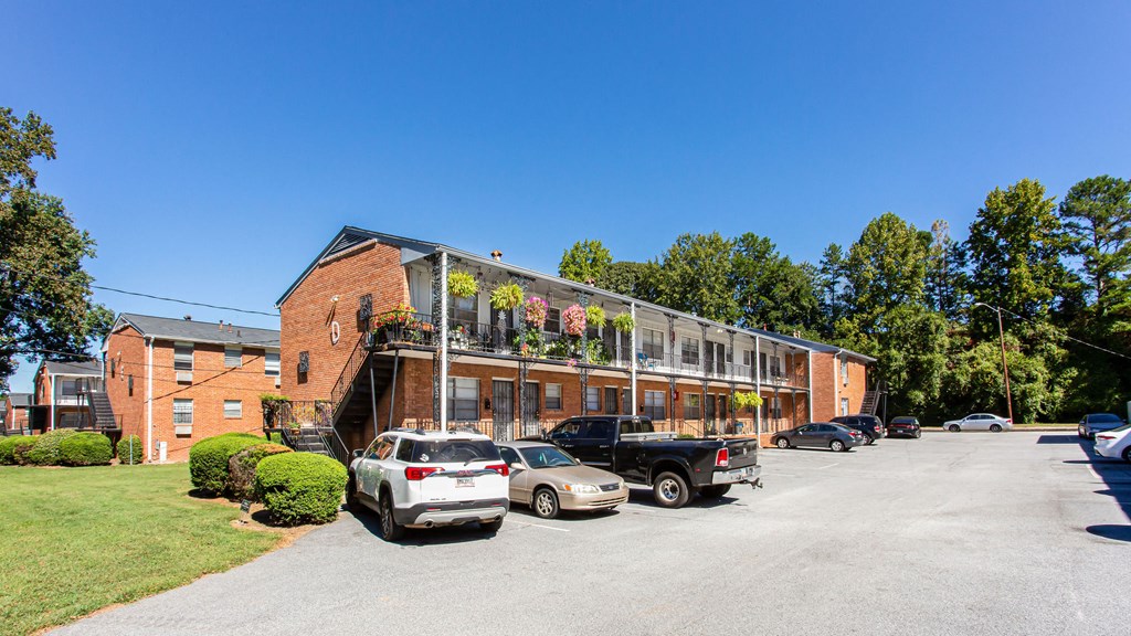 a large brick building with a balcony and a parking lot in front of it