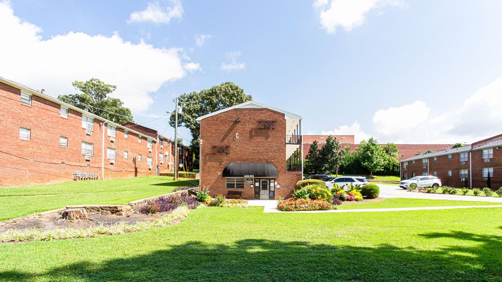 a brick building with a black awning in the middle of a grassy area