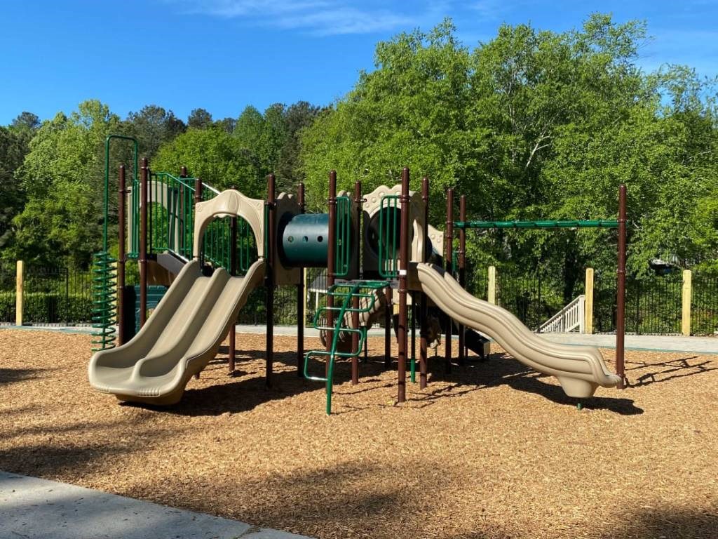 a playground with slides and trees in the background
