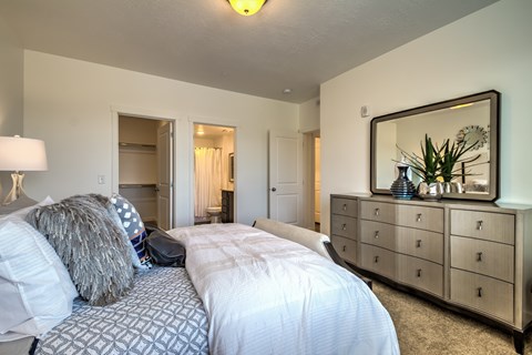A bedroom with a bed, dresser, and mirror.