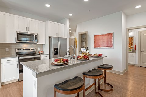A kitchen with white cabinets and a counter with food on it.