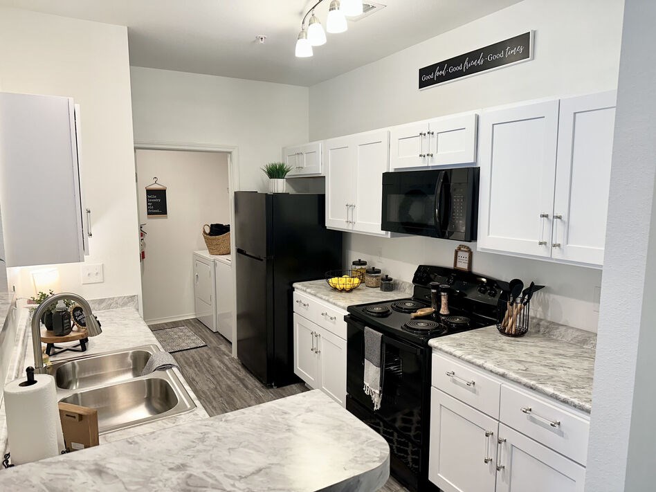 A kitchen with black appliances and white cabinets.