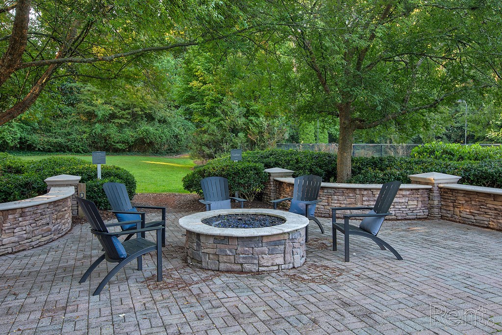 a patio with a fire pit and chairs  at Flats at North Springs, Sandy Springs