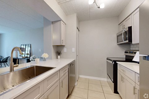 A kitchen with a sink, stove, and microwave.