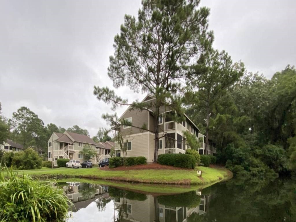 an apartment building sits on the grass next to a body of water