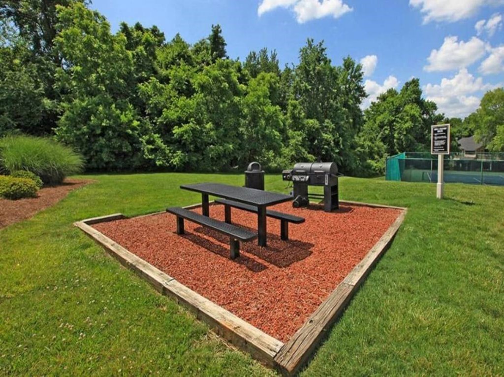 a picnic table and a grill in a park