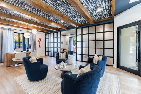 A living room with blue chairs and a wooden ceiling.