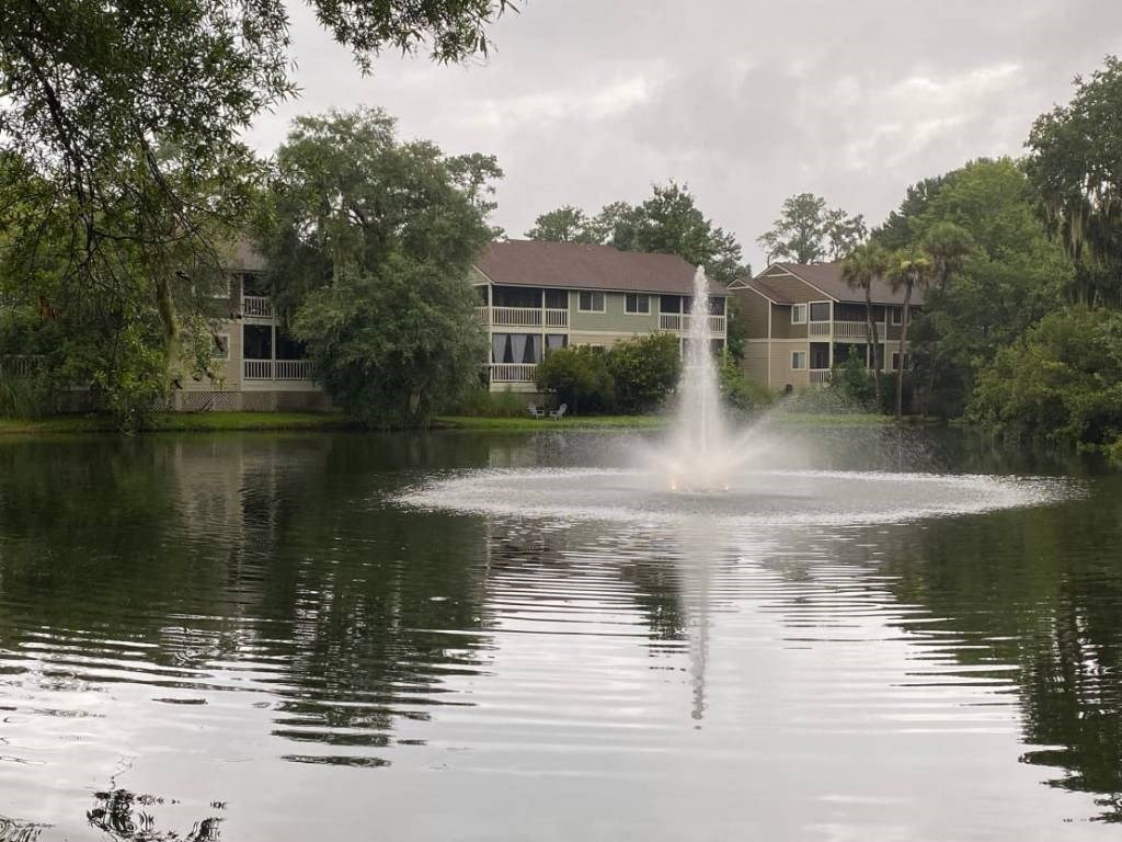 a fountain in the middle of a lake in front of an apartment building