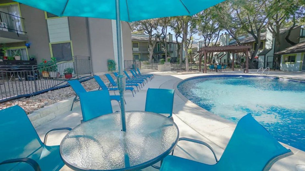 a swimming pool with a table and chairs next to it at Elevate at Huebner Grove, San Antonio