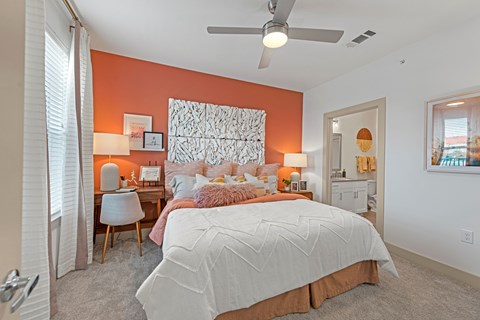 A bedroom with a large bed and a ceiling fan.