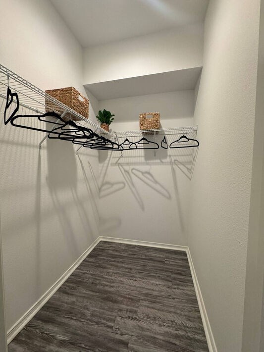 A hallway with a white wall and a grey carpet.