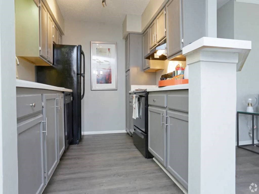 a kitchen with gray cabinets and a black refrigerator