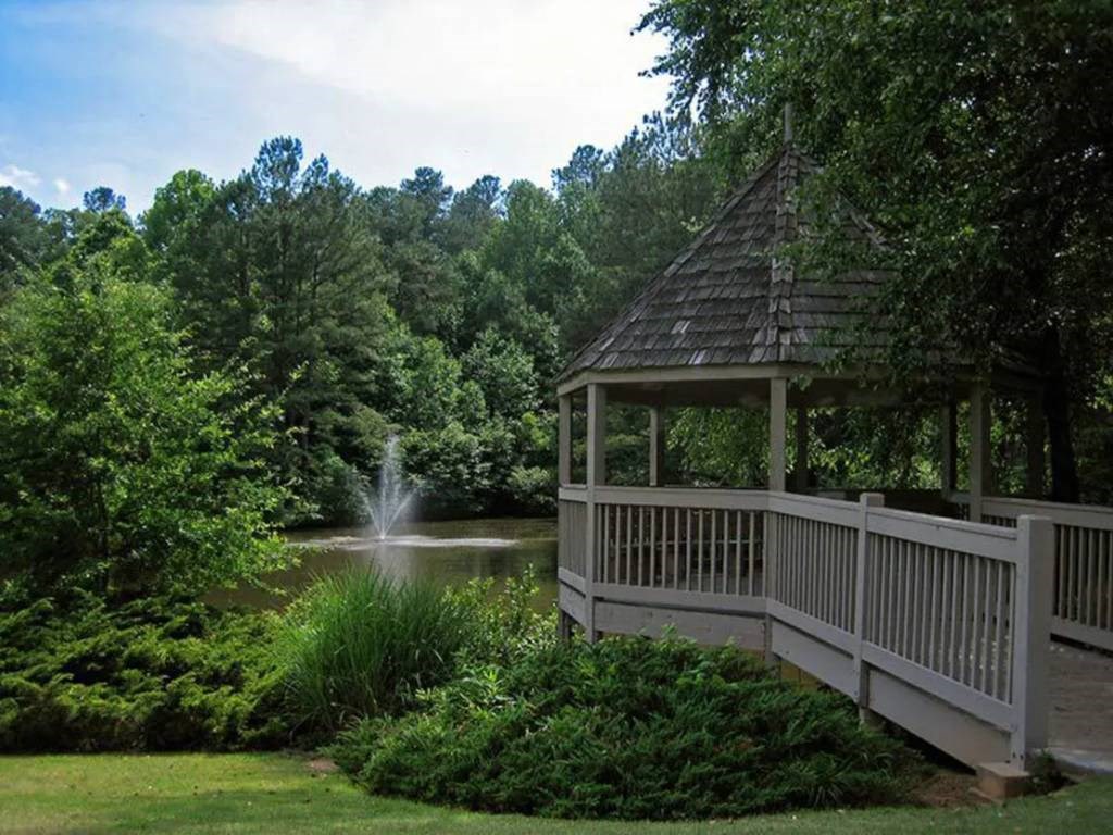 a gazebo overlooking a pond with a fountain