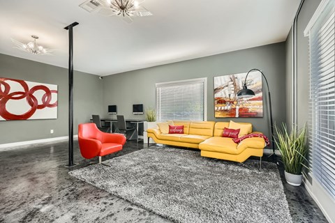 A living room with a yellow couch and a red chair.