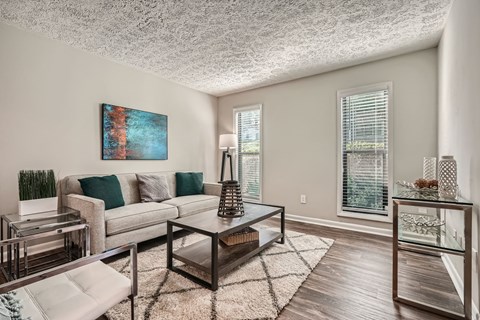 A living room with a grey couch, a coffee table, and a painting on the wall.