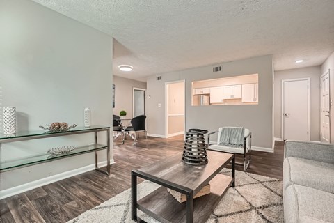 A living room with a glass shelf, a black chair, and a grey couch.