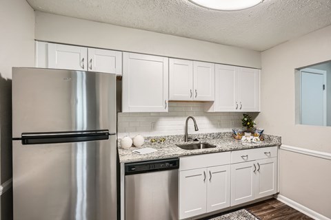 A kitchen with a stainless steel refrigerator and white cabinets.