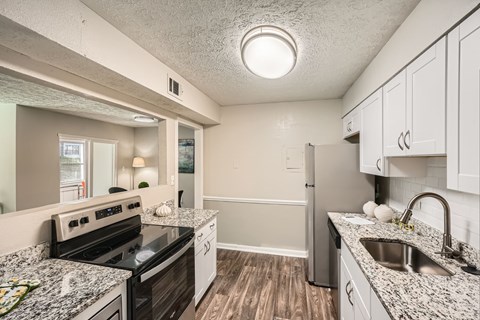 A kitchen with a black stove top oven and a white refrigerator.