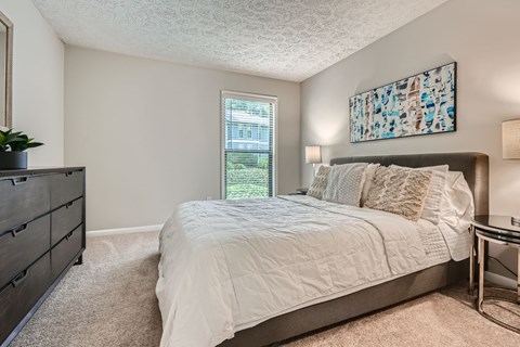 A bedroom with a large bed and a painting on the wall.