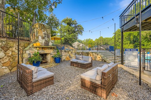 A patio with wicker furniture and a stone fireplace.