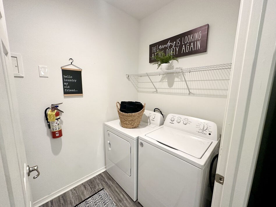 A laundry room with a washer and dryer and a sign on the wall.