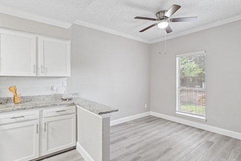 A kitchen with white cabinets and a marble countertop.