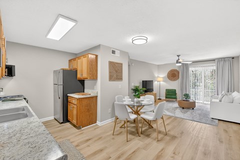 A well-lit, modern kitchen with wooden cabinets and a dining area with a table and chairs.
