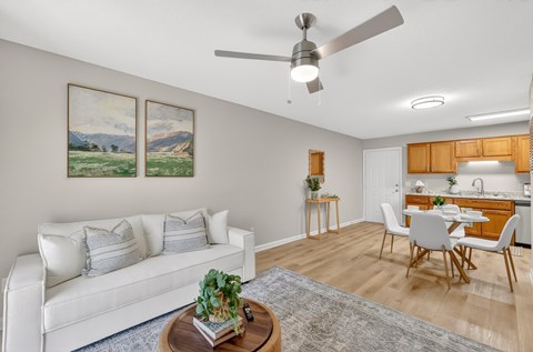 A living room with a white couch and a painting on the wall.