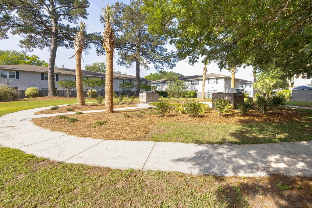 a walkway with trees and houses in the background at Crescent Place Apartments, Savannah, GA