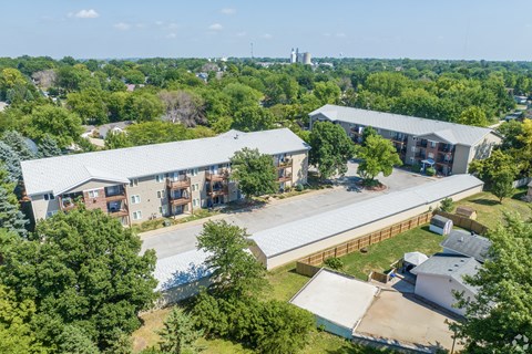 A large building complex surrounded by trees and a parking lot.