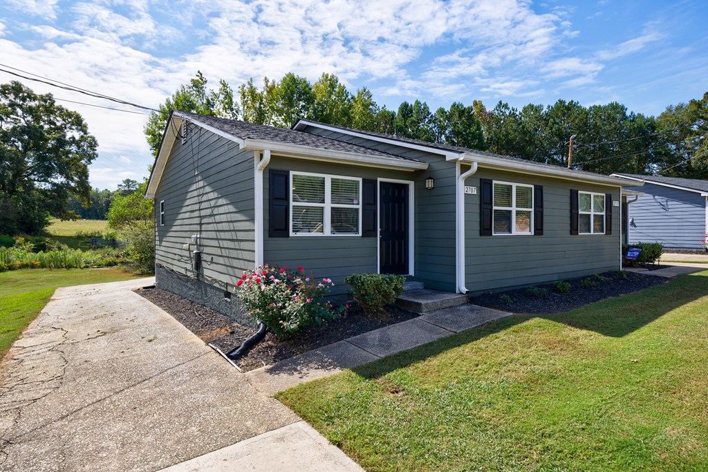 A small grey house with a black door and windows.