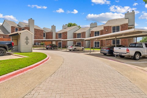 A sunny day at a residential complex with cars parked in the driveway.