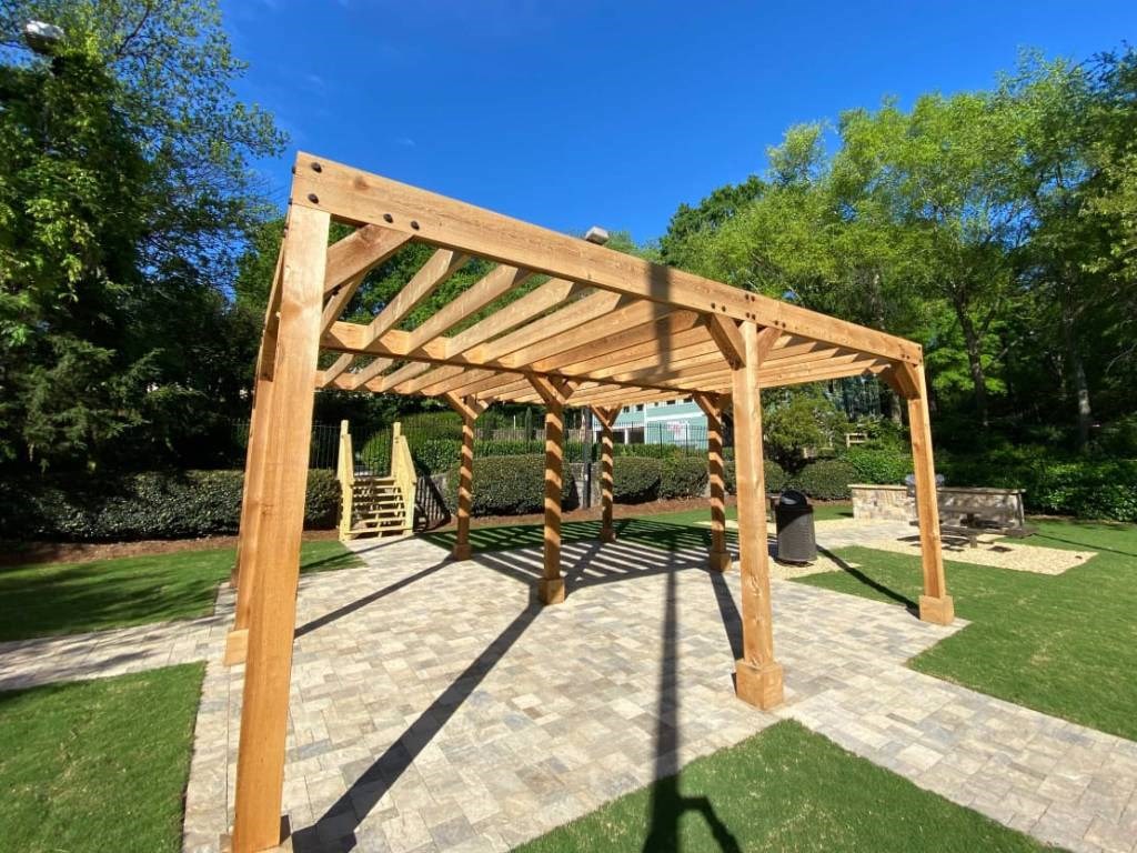 a wooden pergola in a backyard with a stone patio