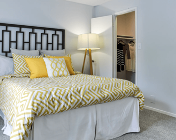 A bed with a yellow and white comforter and two matching pillows.