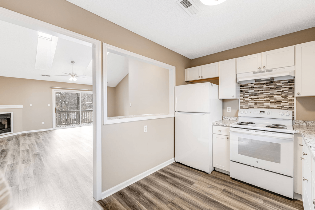 an empty kitchen with white appliances and white cabinets