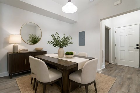 A dining room with a wooden table and white chairs.