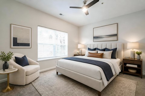 A bedroom with a large bed, a chair, and a ceiling fan.