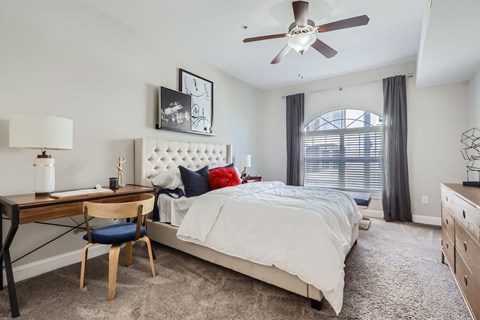 A bedroom with a bed, desk, and chair.